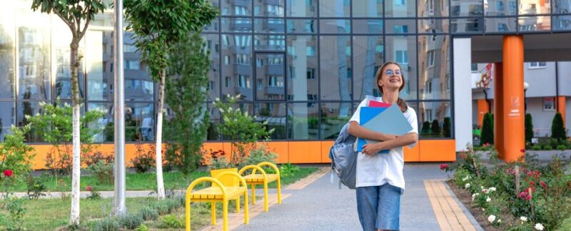 Ecolière avec un cahier dans les mains coucher de soleil sur fond d'école va à l'école. meilleures universités privées en France