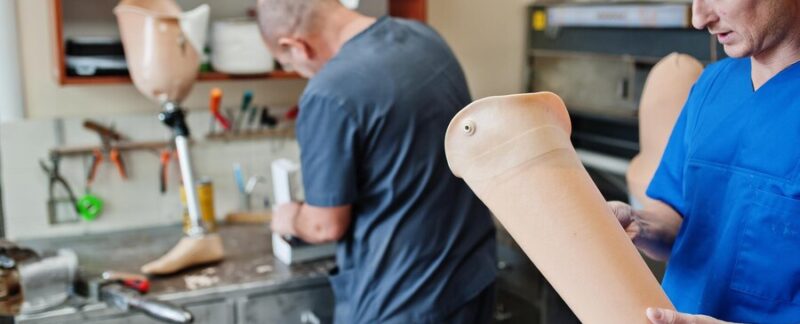 Deux ouvriers prothésistes fabriquent une prothèse de jambe en travaillant dans un laboratoire. meilleurs orthopédistes du genou