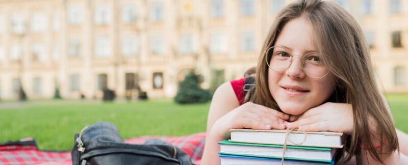 Portrait en gros plan d'une écolière allongée sur une couverture avec des livres. Les  meilleures écoles publiques de France