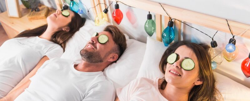 Amis avec une tranche de concombre sur les yeux, allongés dans un lit décoré. meilleurs centres du sommeil