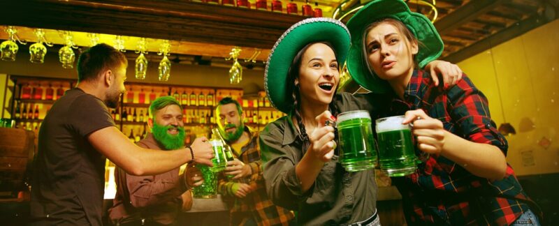 Fête de la Saint-Patrick. Des amis heureux font la fête et boivent de la bière verte. Jeunes hommes et femmes portant des chapeaux verts. Intérieur d'un pub. meilleurs pubs de France