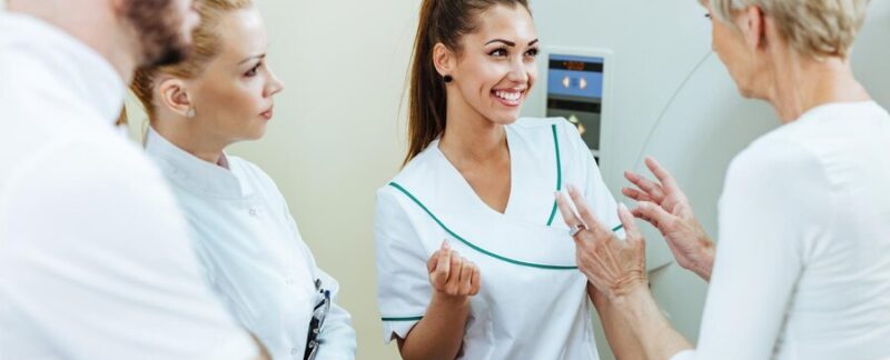 Groupe de professionnels de la santé heureux discutant avec un patient mature avant une procédure d'IRM à l'hôpital. L'accent est mis sur une infirmière heureuse. Les Meilleurs Lymphologues de France