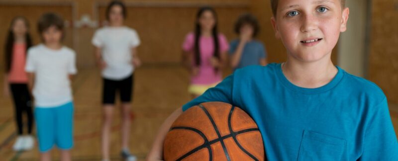 Plan moyen d'enfants jouant au basket dans un gymnase. Les meilleures écoles de basket pour enfants en France