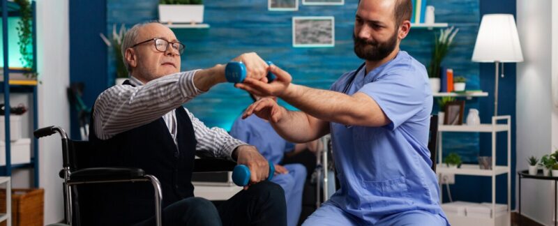 Un médecin aide un retraité en fauteuil roulant à effectuer des exercices de musculation en physiothérapie. meilleurs kinésithérapeutes de France