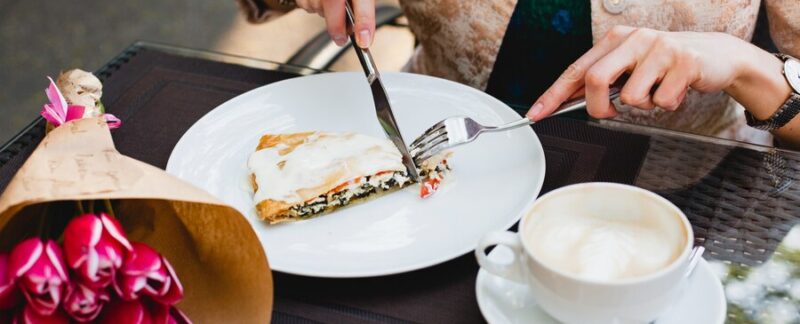 Jeune femme élégante assise dans un café, mangeant une tarte savoureuse. meilleurs restaurants de brunch en France
