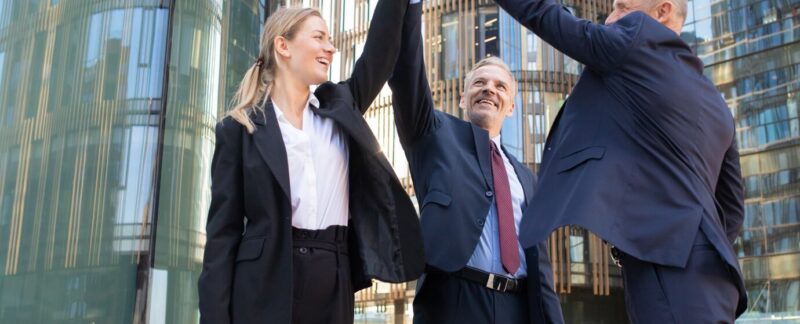 Trois hommes d'affaires joyeux se félicitant et souriant. Des collègues heureux et confiants fêtant ensemble une transaction réussie, debout en plein air et en levant la main. Concept de travail d'équipe et de partenariat. carrières les mieux rémunérées en France