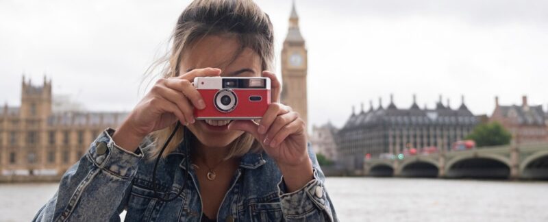 Vue de face d'une femme souriante tenant un appareil photo. meilleurs magasins de photo en France