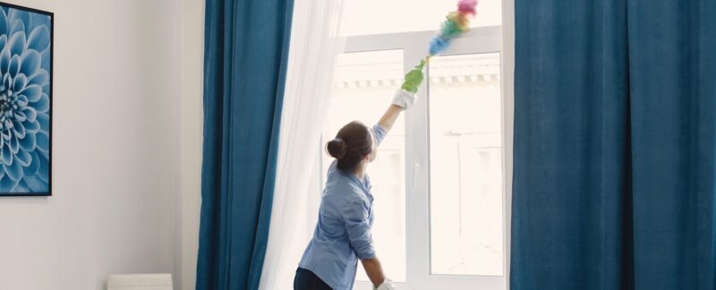 Femme avec une éponge et des gants en caoutchouc nettoyant la maison. Les 10 meilleurs services de lavage de rideaux en France