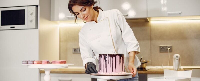 Le pâtissier en uniforme décore le gâteau. Les meilleures écoles de pâtisserie en France