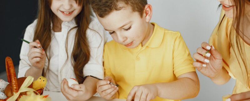 Les enfants peignent des œufs. La mère enseigne aux enfants. Assis à une table blanche. Les 10 meilleures activités pour les enfants d'âge préscolaire en France