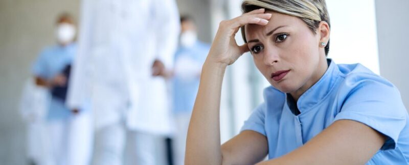 Infirmière angoissée, assise dans un couloir et réfléchissant à quelque chose. cliniques de traitement de l'anxiété en France