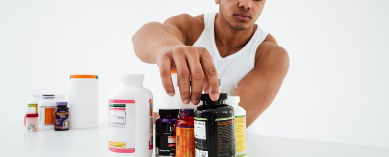 Sportif debout sur un mur blanc tenant des vitamines. meilleurs magasins de produits diététiques