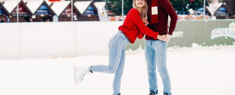 Un joli couple en pull-over rouge s'amuse sur une patinoire. meilleures patinoires de France