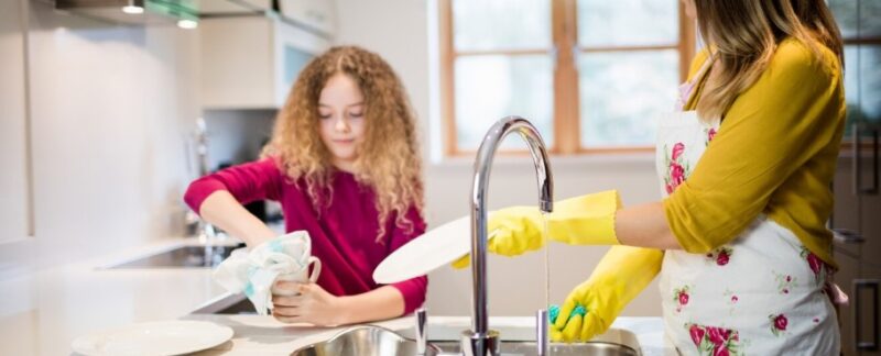 Une mère aidant sa fille à faire la vaisselle dans la cuisine. meilleurs lave-vaisselle en France